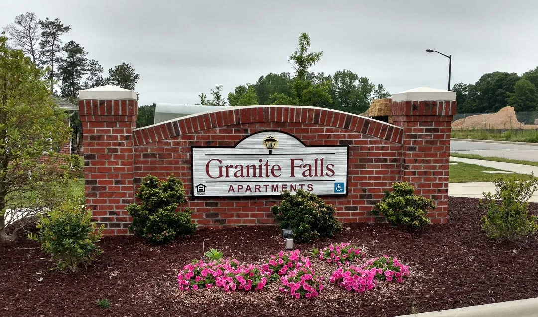 Brick entrance wall with plaque for Granite Falls Apartments