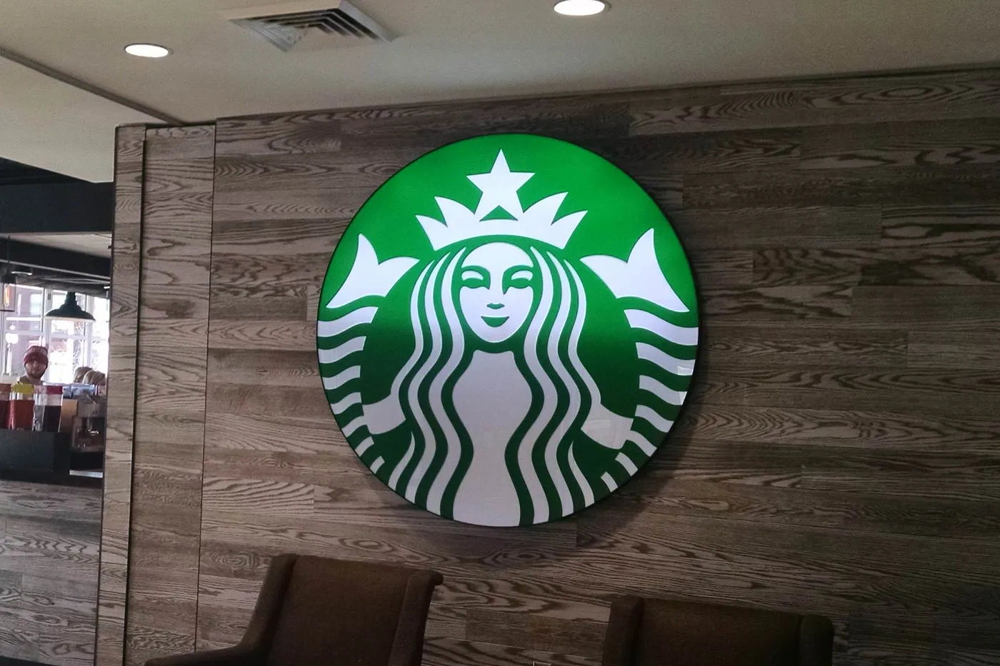 Lit round logo on interior wood wall for Starbucks